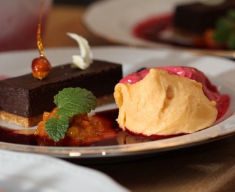 Chokladkaka på hasselnötsbotten med två sorters sorbet, varma hjortron och björnbärssås