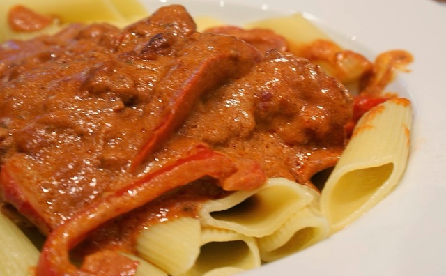 Kylling i tomat med bacon, tomat og røde peberfrugter på frisk pasta