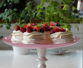 Söta små marängbakelser med lemon curd, grädde och färska bär