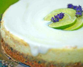 Cheeseckake och topping med 5 skivor lime och lilla blommor.