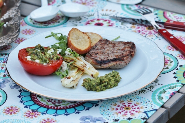 Grillad entrecôte med tillbehör: tomat, salladslök, fetaost, mandelpesto, ruccola och hemmafixade crostini