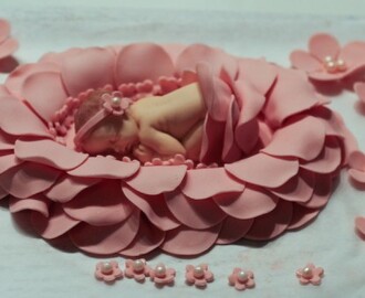 Ristiäiskoristeen tekoa, vauva kukan terälehtien keskellä.