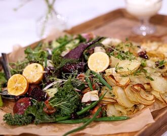 En träbricka med rostad potatis Provencale, med citronbakade rödbetor och sallad.