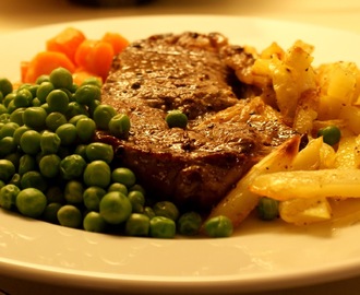 Steak med hvidløgsdampede gulerødder, grønne ærter, ovnbagt frites & brun sauce