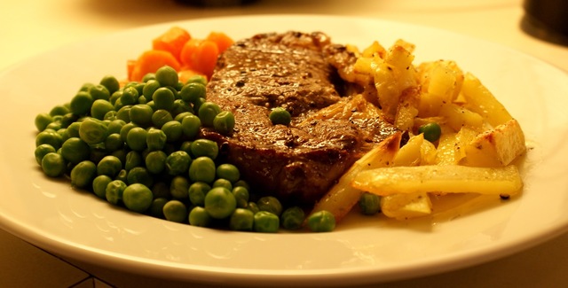 Steak med hvidløgsdampede gulerødder, grønne ærter, ovnbagt frites & brun sauce