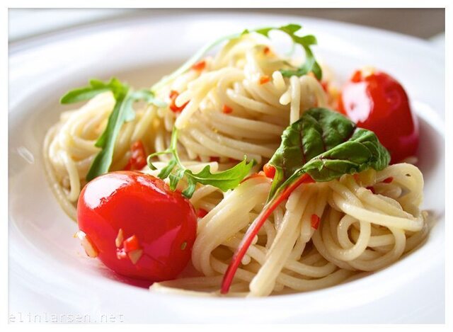 Spaghetti i olivenolje med chilli og hvitløk, servert med stekte perletomater og et dryss av ruccola