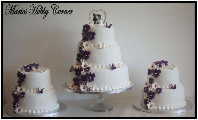 Stor bröllopstårta  i vitt och lila med orkidéer och frangipani