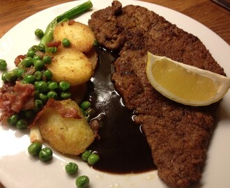 Hemmagjord wienerschnitzel med gröna ärtor och stekt potatis