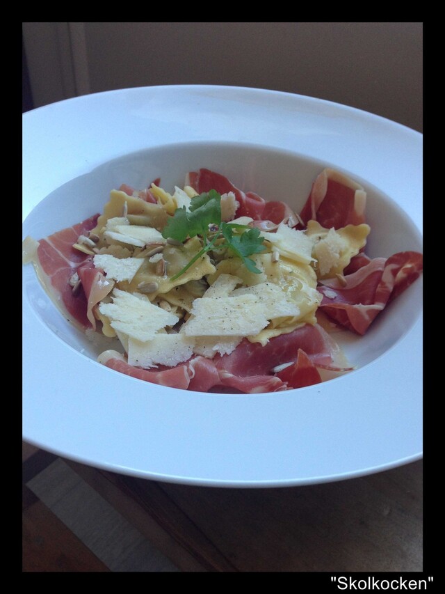 Fylld ravioli med serranoskinka, brynt smör, rostade solroskärnor och hyvlad parmesan