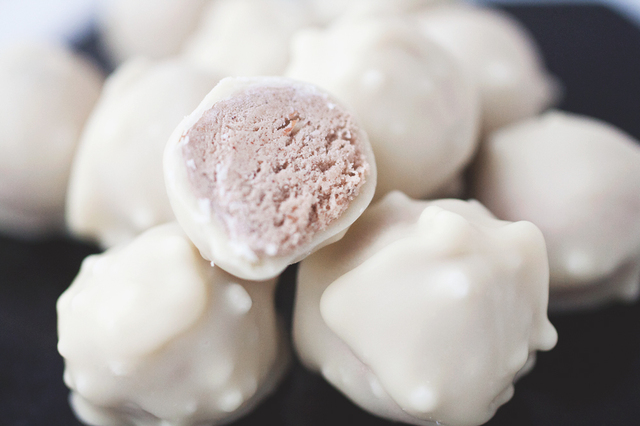 Pepparkakssmakande proteinkolabollar med mandelkrisp, doppade i vit choklad