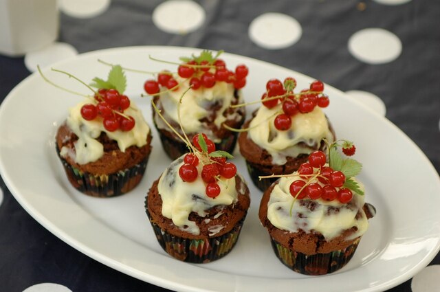 Pepparkakscupcakes med vit choklad- och citrontopping med röda vinbärsklasar